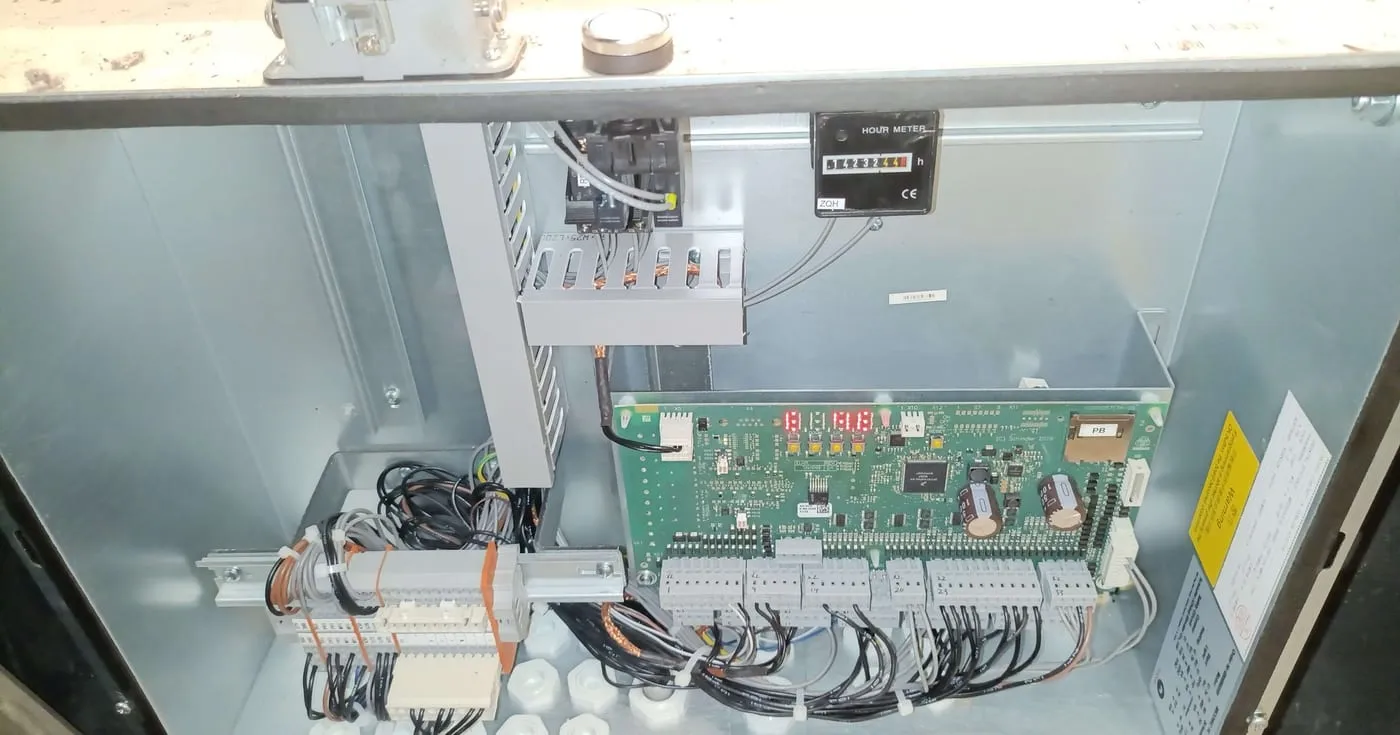 Tablero de control de la escalera abierto: la tarjeta electrónica con su display, el contador de horas, los contactores y las borneras con su cableado.